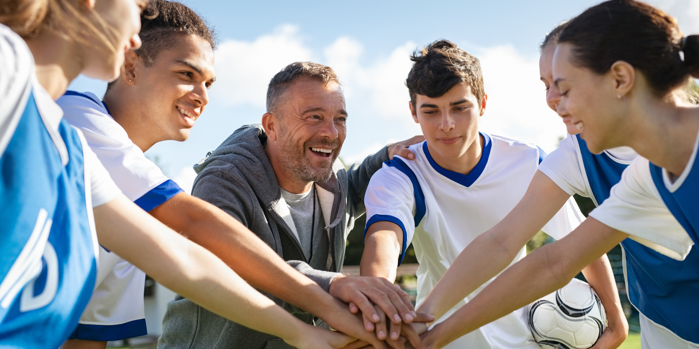 Teenagers and Coach in a huddle before a game