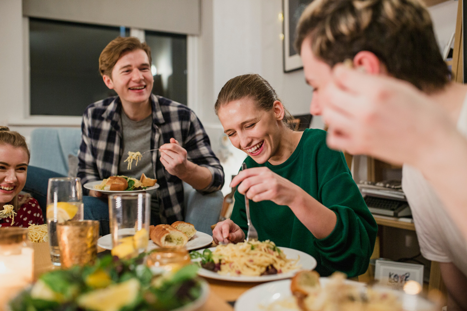 Four people sat at a table eating a meal and laughing 