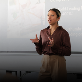 female student stood in front of a screen giving lecture