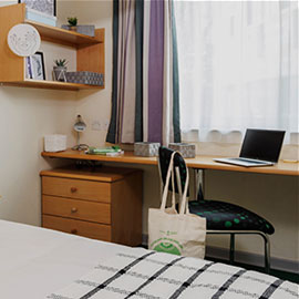 room with desk chair and laptop in front of a window - student accommodation