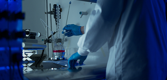 a person in a lab coat and gloves using lab equipment