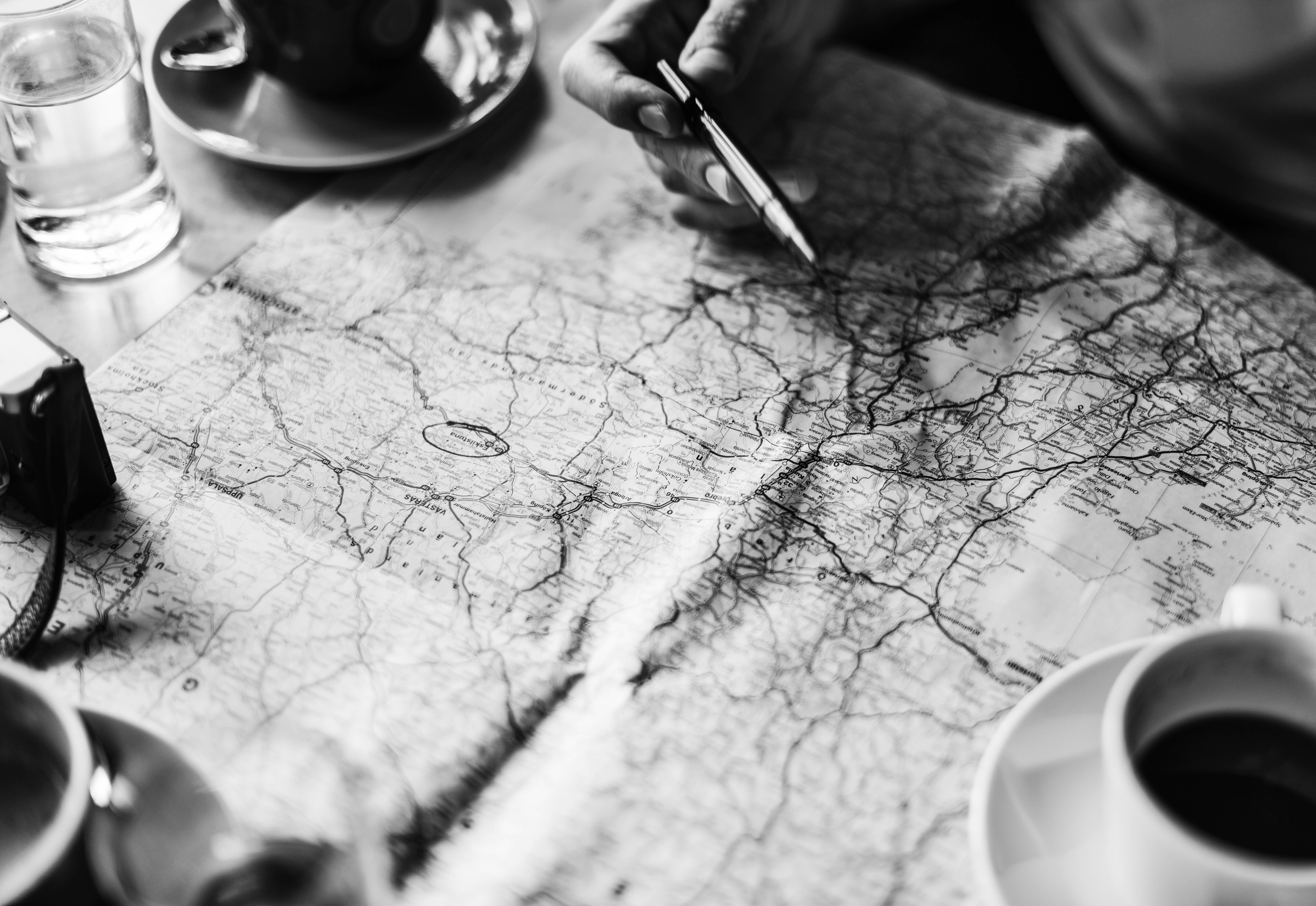 Map with coffee and hand holding a pen
