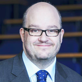 a man wearing glasses and smiling at the camera