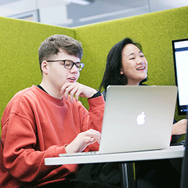 a group of people sitting in front of a laptop computer