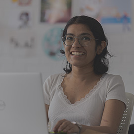 Student smiling in class with laptop.