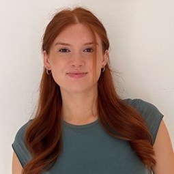 Girl with ginger hair wearing dark top smiling at camera