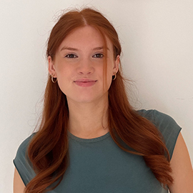 Girl with ginger hair wearing dark top smiling at camera 