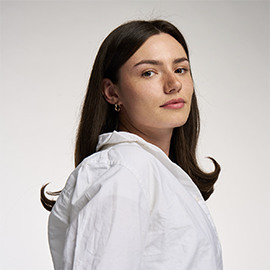 Girl with brown hair, wearing white top, smiling at camera