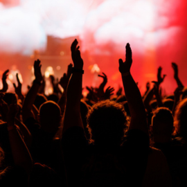 hands raised at a concert, set against bright red lights